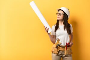 thoughtful handywoman holding and looking at blueprint on yellow background